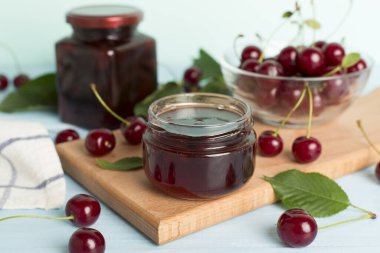 Ahşap masada ev yapımı kiraz reçelli kavanoz.