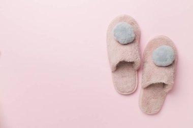 Soft pink slippers on color background, top view