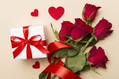 Valentines day gift box with red roses on color background, top view