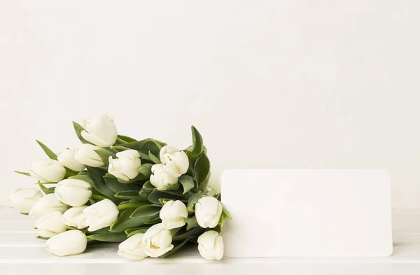 White tulip bouquet with card on table