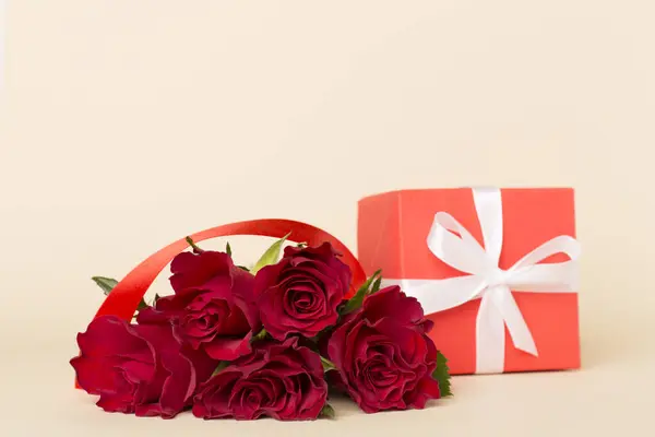 Valentines day red roses with gift box on color table