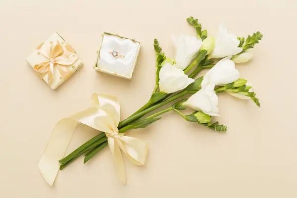 カラーバックグラウンドのダイヤモンドリング トップビューの白いフレンチの花とギフトボックス — ストック写真