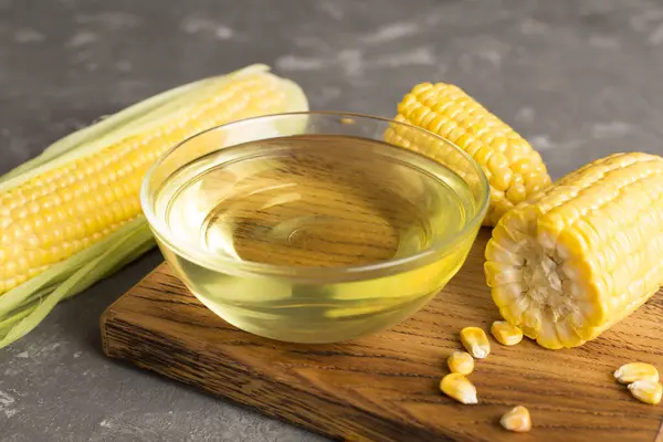 Corn oil with fresh cobs on concrete table