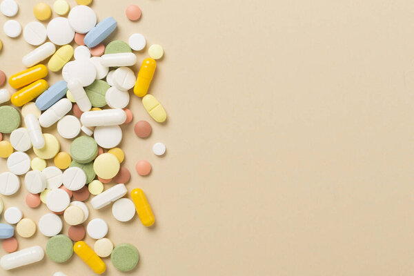 Different medical pills and capsules on color background, top view