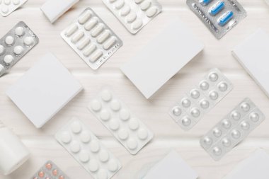 Su toplamada ve kutularda farklı haplar ve ahşap arka planda üst görünüm.