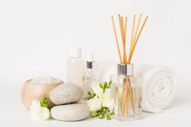 Beyaz arkaplanda frezya çiçeği ve aroma yayıcı içeren spa kompozisyonu