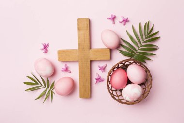 Çapraz ve arka planda palmiye yaprakları olan pembe Paskalya yumurtaları.