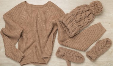 Ahşap arka planda eldivenleri olan kazak ve kış şapkası..