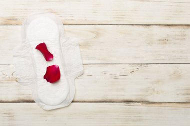 Ahşap arka planda kırmızı yapraklı regl yastığı.