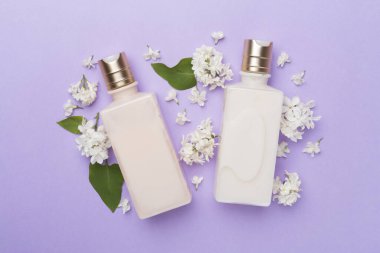 Renkli arka planda kozmetik şişeleri ve çiçekleri olan kompozisyon, üst görünüm