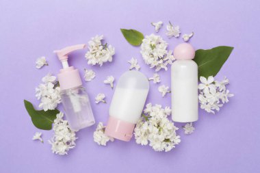 Renkli arka planda kozmetik şişeleri ve çiçekleri olan kompozisyon, üst görünüm