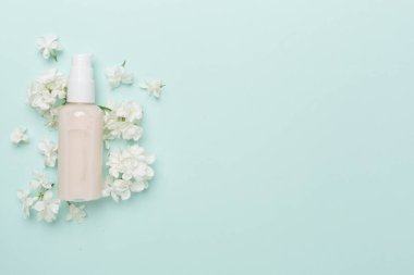 Renkli arka planda kozmetik şişesi ve çiçekli kompozisyon, üst görünüm