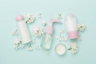 Renkli arka planda kozmetik şişesi ve çiçekli kompozisyon, üst görünüm