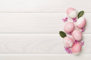 Ahşap arka planda dekoru olan pembe Paskalya yumurtaları.