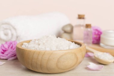 Ahşap masanın üzerinde pembe güller olan spa kompozisyonu