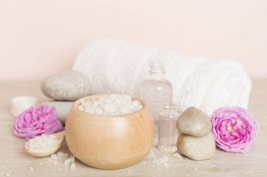 Ahşap masanın üzerinde pembe güller olan spa kompozisyonu