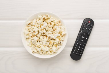 Tahta arka planda patlamış mısır ve televizyon uzaktan kumandası