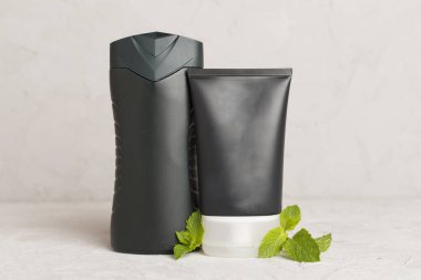 Erkekler, arka planda nane yapraklı kozmetik şişeleri.