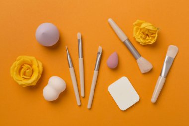 Renk arkaplanında makyaj fırçaları ve süngerler, üst görünüm