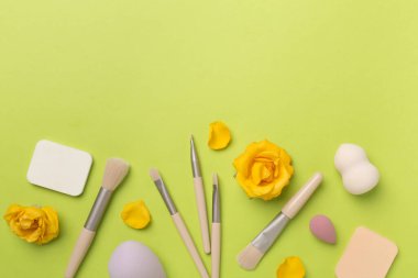 Renk arkaplanında makyaj fırçaları ve süngerler, üst görünüm