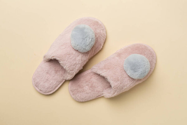 Soft pink slippers on color background, top view