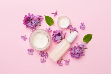 Renkli arka planda kozmetik şişeleri ve çiçekleri olan kompozisyon, üst görünüm