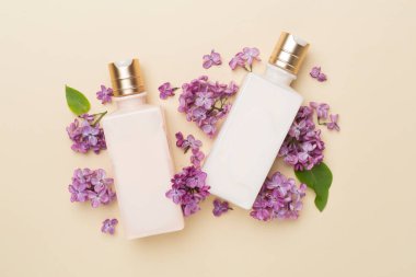 Renkli arka planda kozmetik şişeleri ve çiçekleri olan kompozisyon, üst görünüm