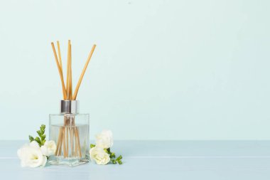 Tahta masa üzerinde frezya çiçeği ve aroma yayıcı içeren spa kompozisyonu