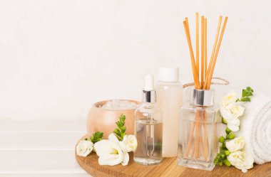 Tahta masa üzerinde frezya çiçeği ve aroma yayıcı içeren spa kompozisyonu