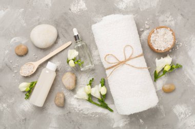 Beton zemin üzerinde spa ürünleri ve çiçeklerle yatıyordu