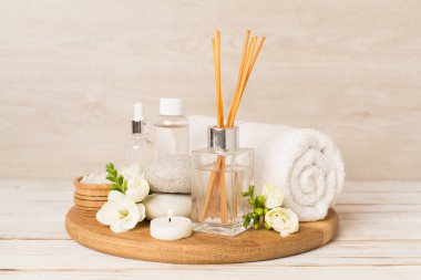 Tahta masa üzerinde frezya çiçeği ve aroma yayıcı içeren spa kompozisyonu