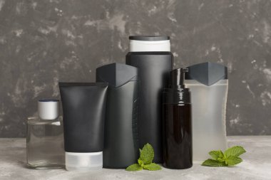 Erkekler kozmetik şişeleri ve ahşap masa üzerinde nane yaprakları.