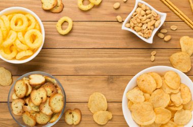 Ahşap arka planda çeşitli sağlıksız atıştırmalıklar.