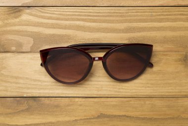 Ahşap zemin üzerinde güneş gözlüğü, üst görünüm.