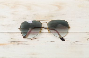 Ahşap zemin üzerinde güneş gözlüğü, üst görünüm.