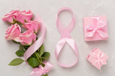 Pembe güller, hediye kutusu ve beton arka planda sekiz şeritten oluşan kompozisyon, üst manzara. Kadınlar Günü konsepti