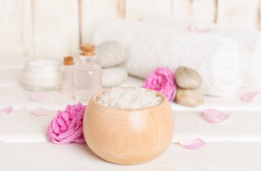 Ahşap masanın üzerinde pembe güller olan spa kompozisyonu