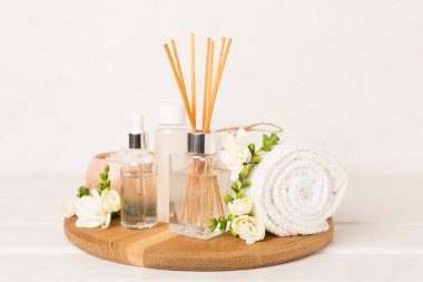 Tahta masa üzerinde frezya çiçeği ve aroma yayıcı içeren spa kompozisyonu