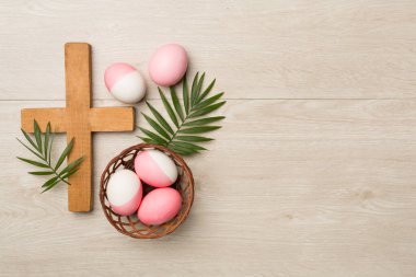 Ahşap arka planda haçlı ve yapraklı pembe Paskalya yumurtaları.