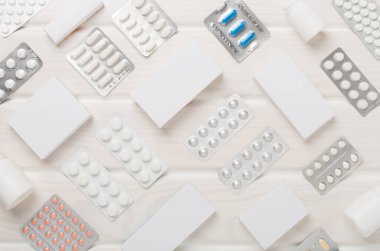 Su toplamada ve kutularda farklı haplar ve ahşap arka planda üst görünüm.