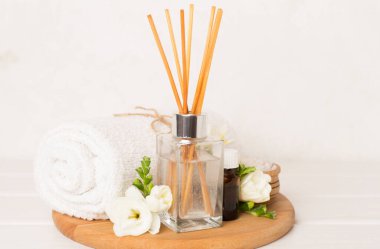 Tahta masa üzerinde frezya çiçeği ve aroma yayıcı içeren spa kompozisyonu