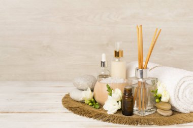 Tahta masa üzerinde frezya çiçeği ve aroma yayıcı içeren spa kompozisyonu