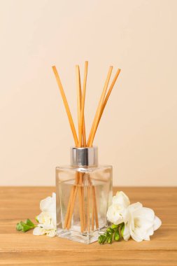 Tahta masa üzerinde frezya çiçeği ve aroma yayıcı içeren spa kompozisyonu