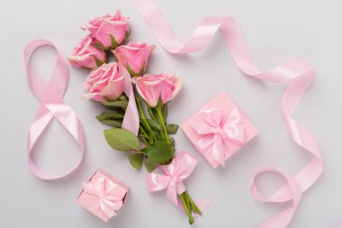 Pembe güllü kompozisyon, hediye kutusu ve arka planda sekizli kurdele, üst manzara. Kadınlar Günü konsepti