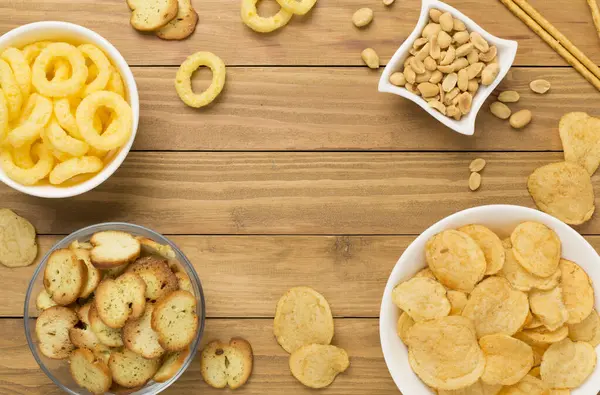 Ahşap arka planda çeşitli sağlıksız atıştırmalıklar.