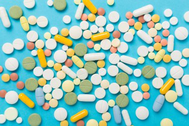 Farklı ilaç ve kapsüller. Renkli arka plan, üst görünüm.