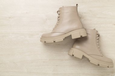 Ahşap arka planda bej renkli moda botlar, üst manzara.