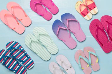 Ahşap arka planda birçok parlak parmak arası terlik, üst görünüm