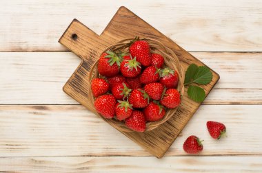 Çilekler kasede, ahşap arka planda, üst manzara.