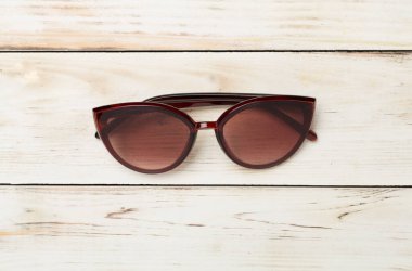 Ahşap zemin üzerinde güneş gözlüğü, üst görünüm.